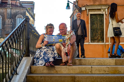 Tourists sitting on a Venice bridge